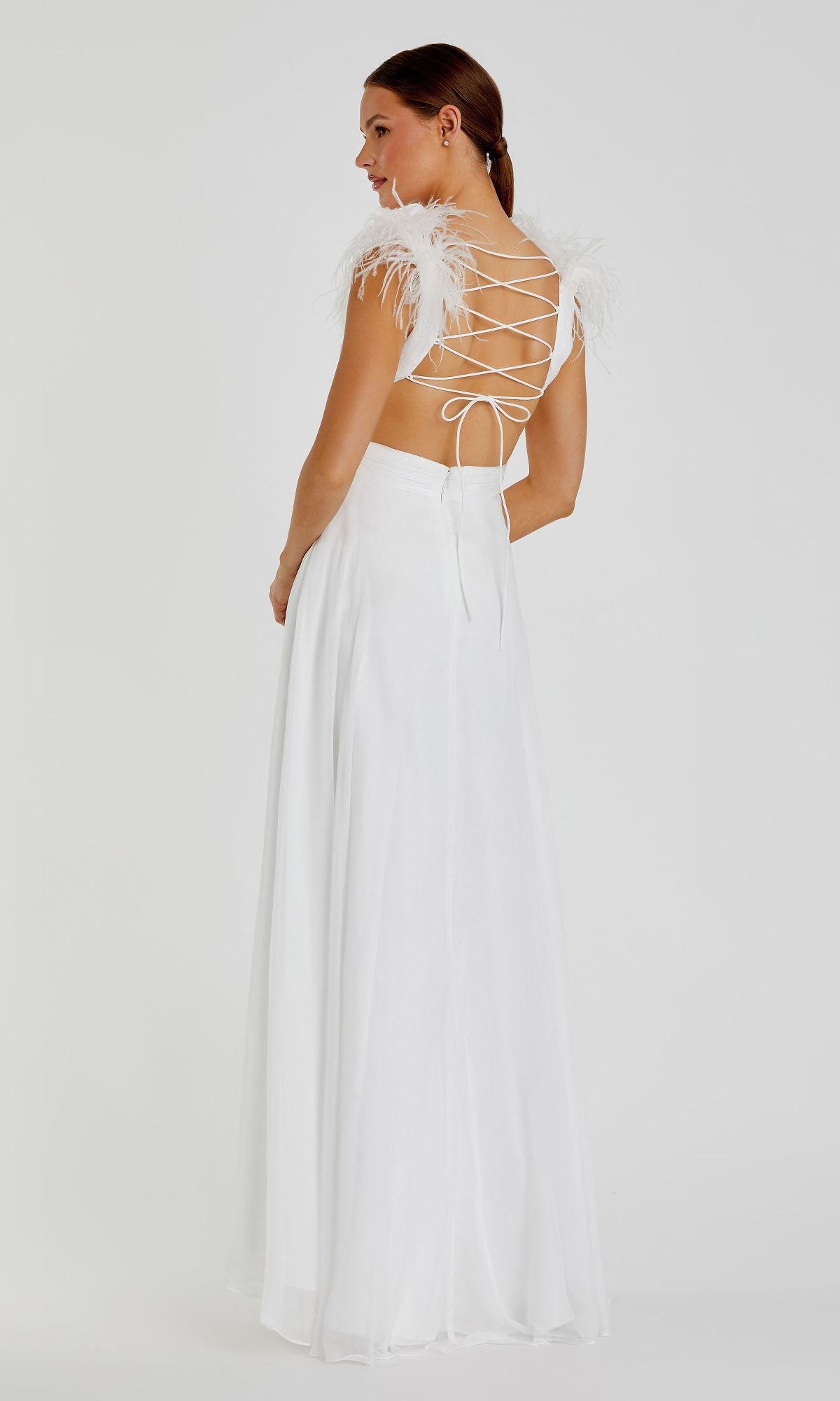 A woman stands against a plain background wearing the Mac Duggal 68113 Feather-Trim Long Formal Dress, featuring strappy open back, feathered shoulder details, and a floor-length white skirt.